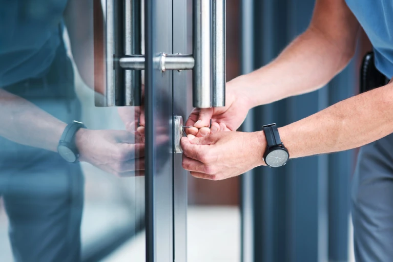 Locksmith installing a lock on a commercial glass door, representing master key system planning, installation, and walk-through services in Florida