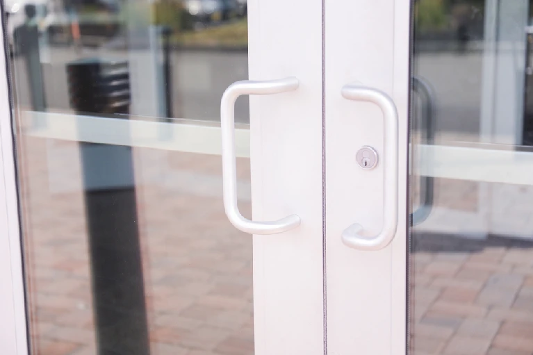 Commercial door lock replacement—close-up of a storefront glass door with handle and keyed cylinder in Orlando, Florida